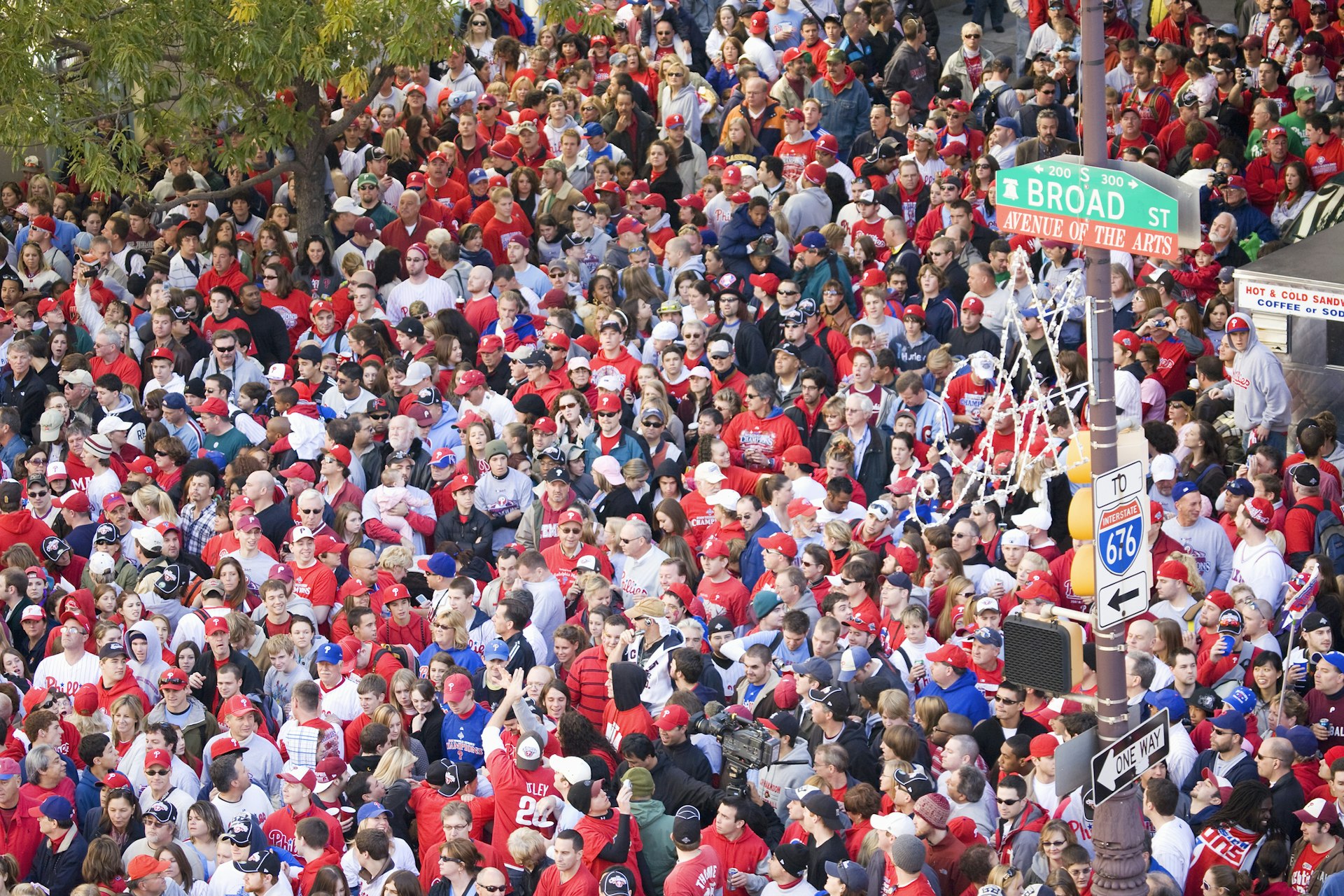 Philadelphia Phillies fans, mainly dressed in red, crowd together down a street in celebration of winning the World Series