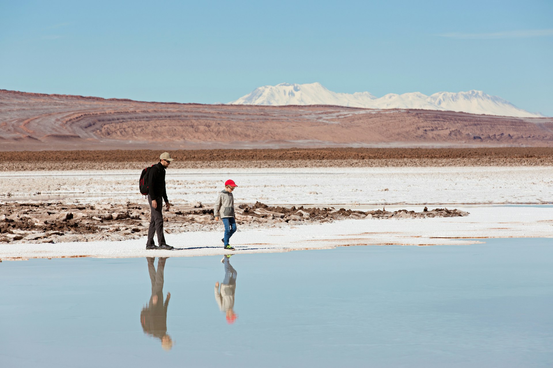 Un padre y su hijo caminan junto a un lago salado en una vasta zona desértica
