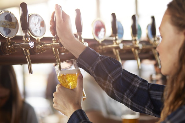 A bartender pours a beer from a tap into a glass