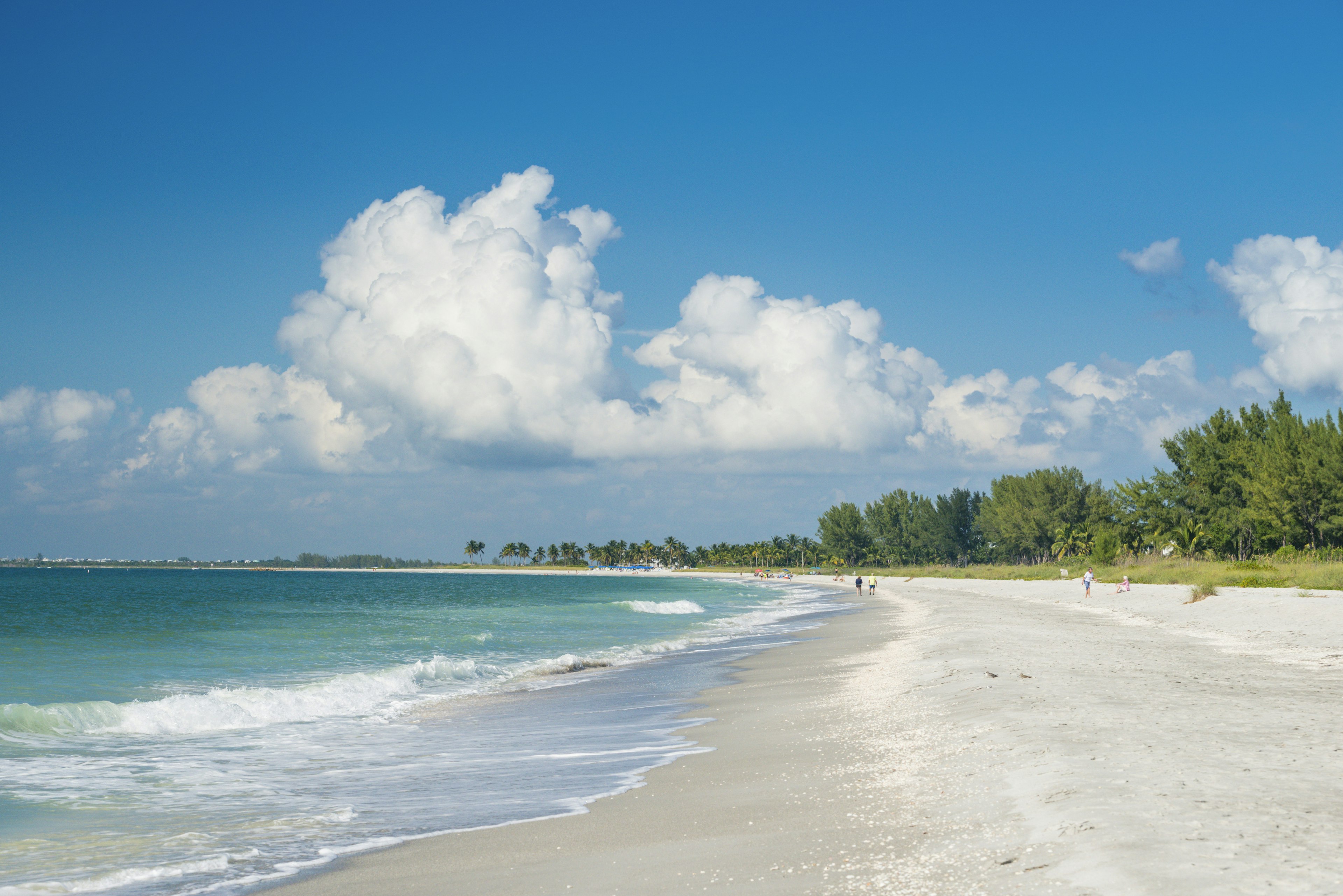 A curving beach under cloudy skies with blue sky above