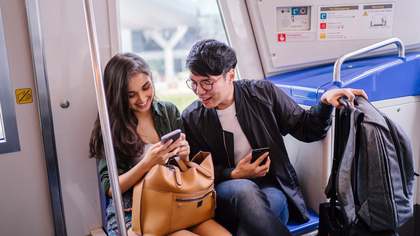 A young diverse interracial Asian couple are smiling as they sit in a train and look a a smartphone together. A Korean man and his Indian companion are smiling as they take public transportation.; Shutterstock ID 1368668465; full: Singapore getting around; gl: 65050; netsuite: Online ed; your: Claire Naylor
1368668465