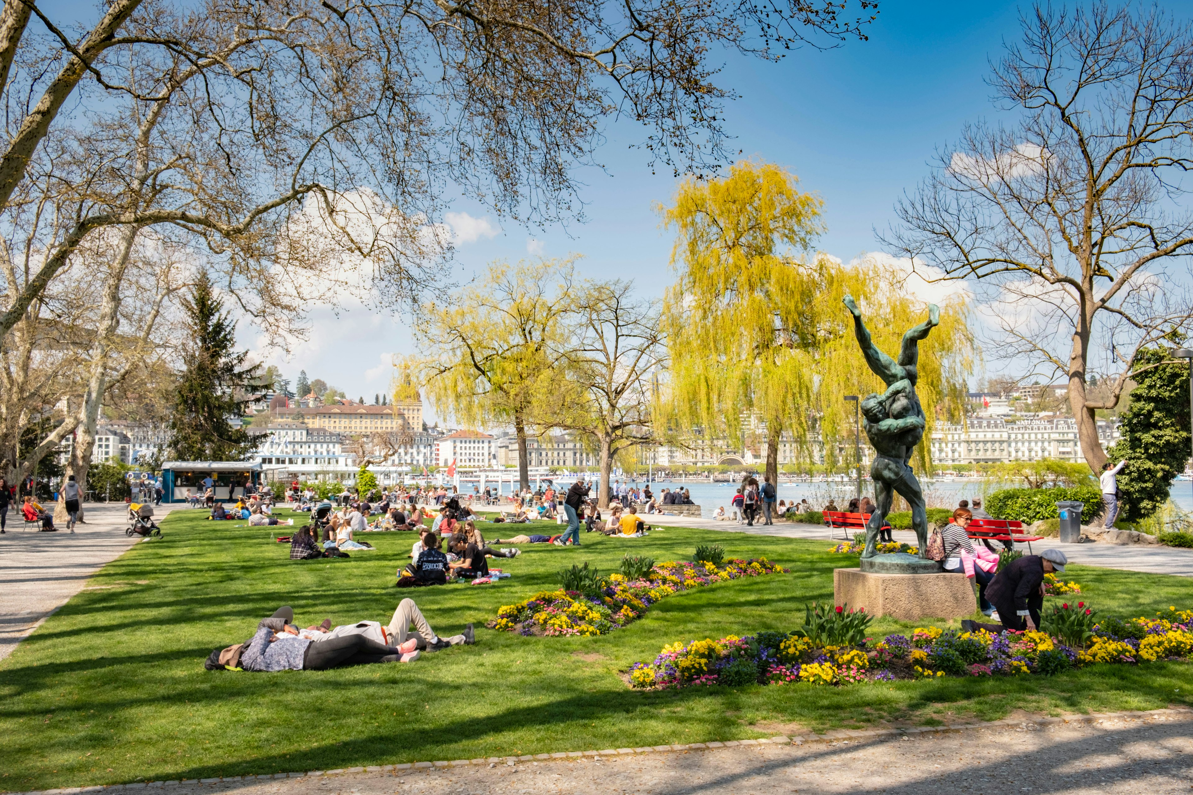 People lie on the grass at a lakeside park on a sunny day