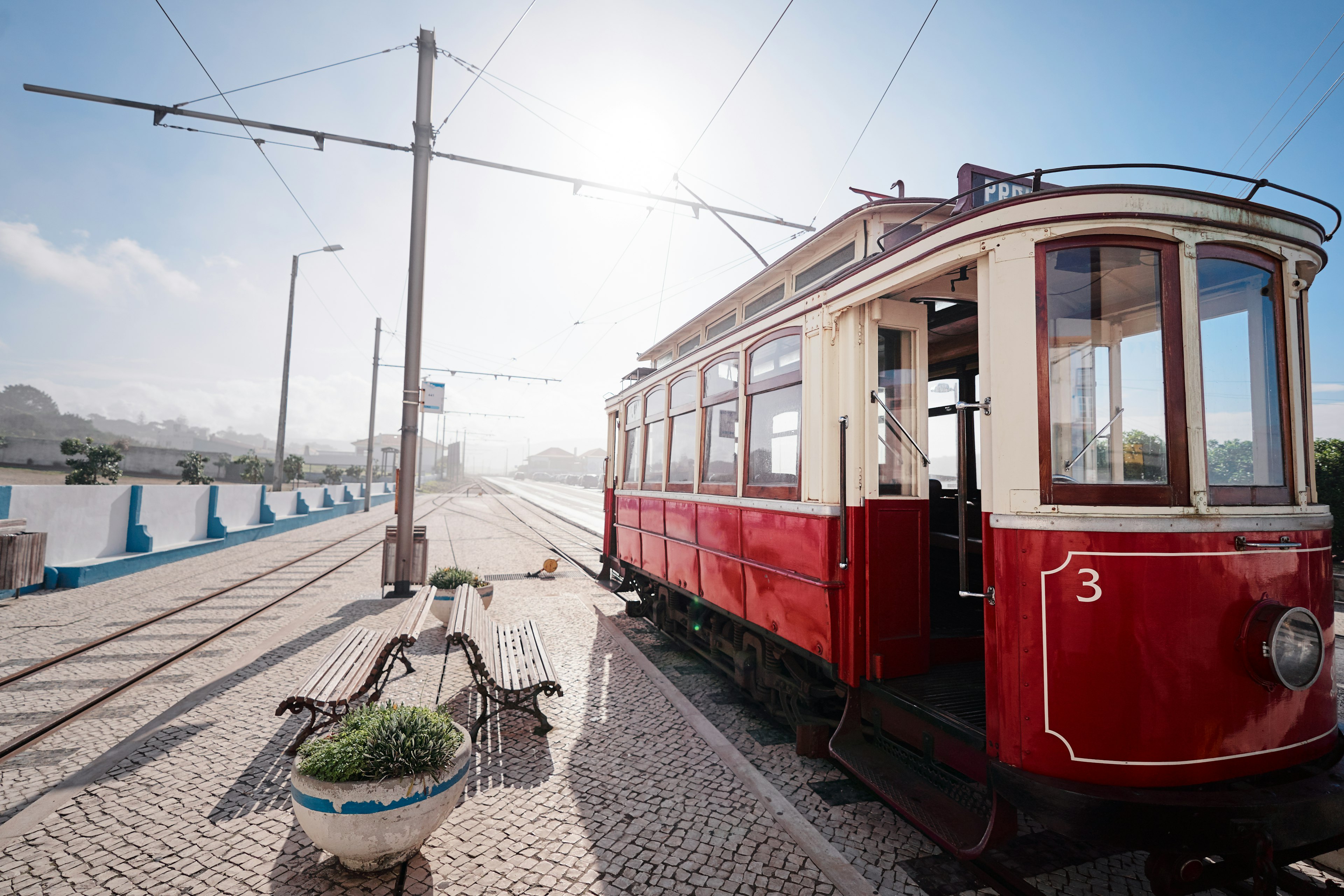 A red and white tram in Portugal sits stationary, ready to pick up passengers