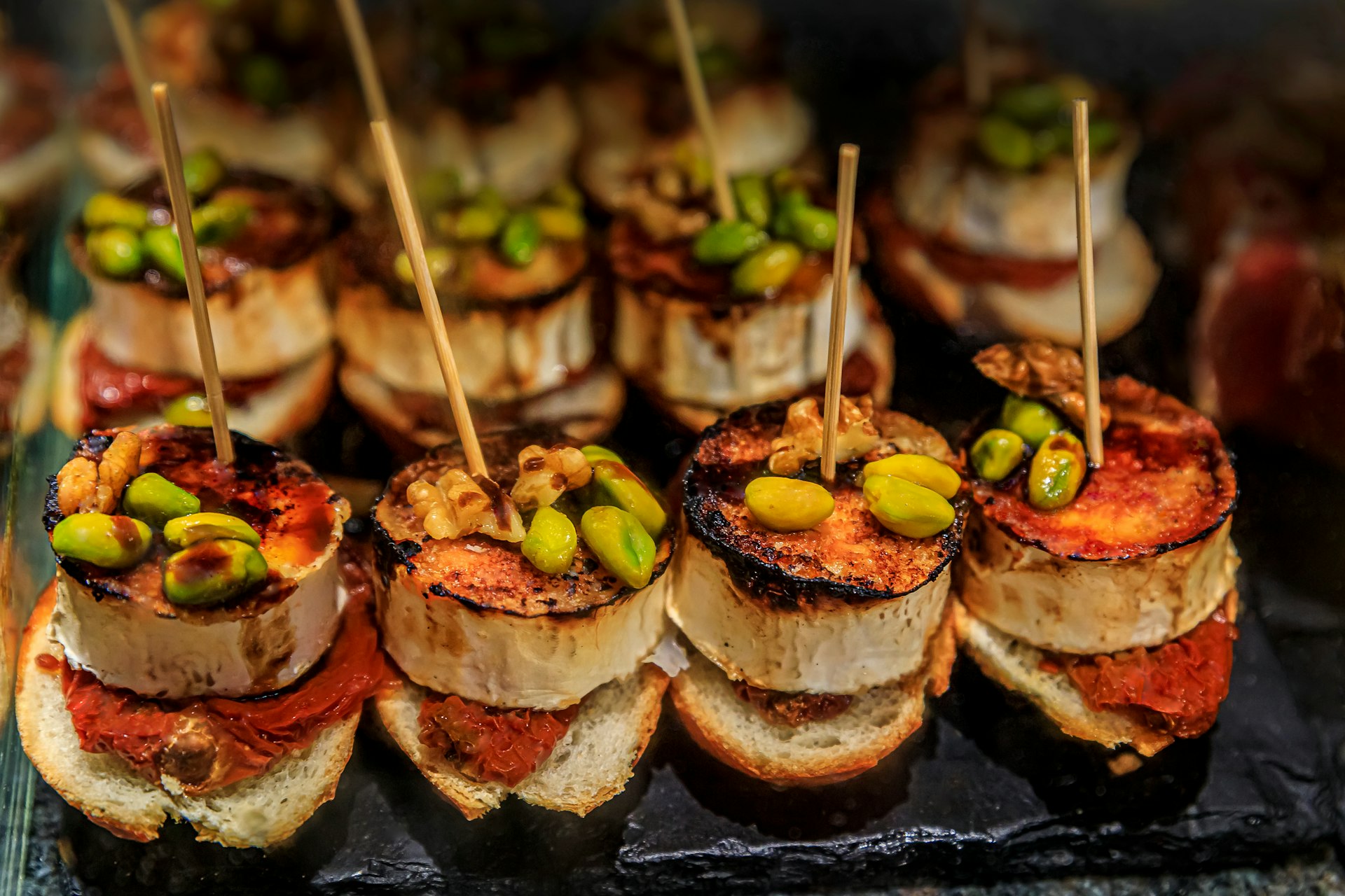 Traditional Spanish pintxos with goat cheese, pistachios, walnuts and red piquillo pepper at a bar in San Sebastian Donostia, Basque Country, Spain