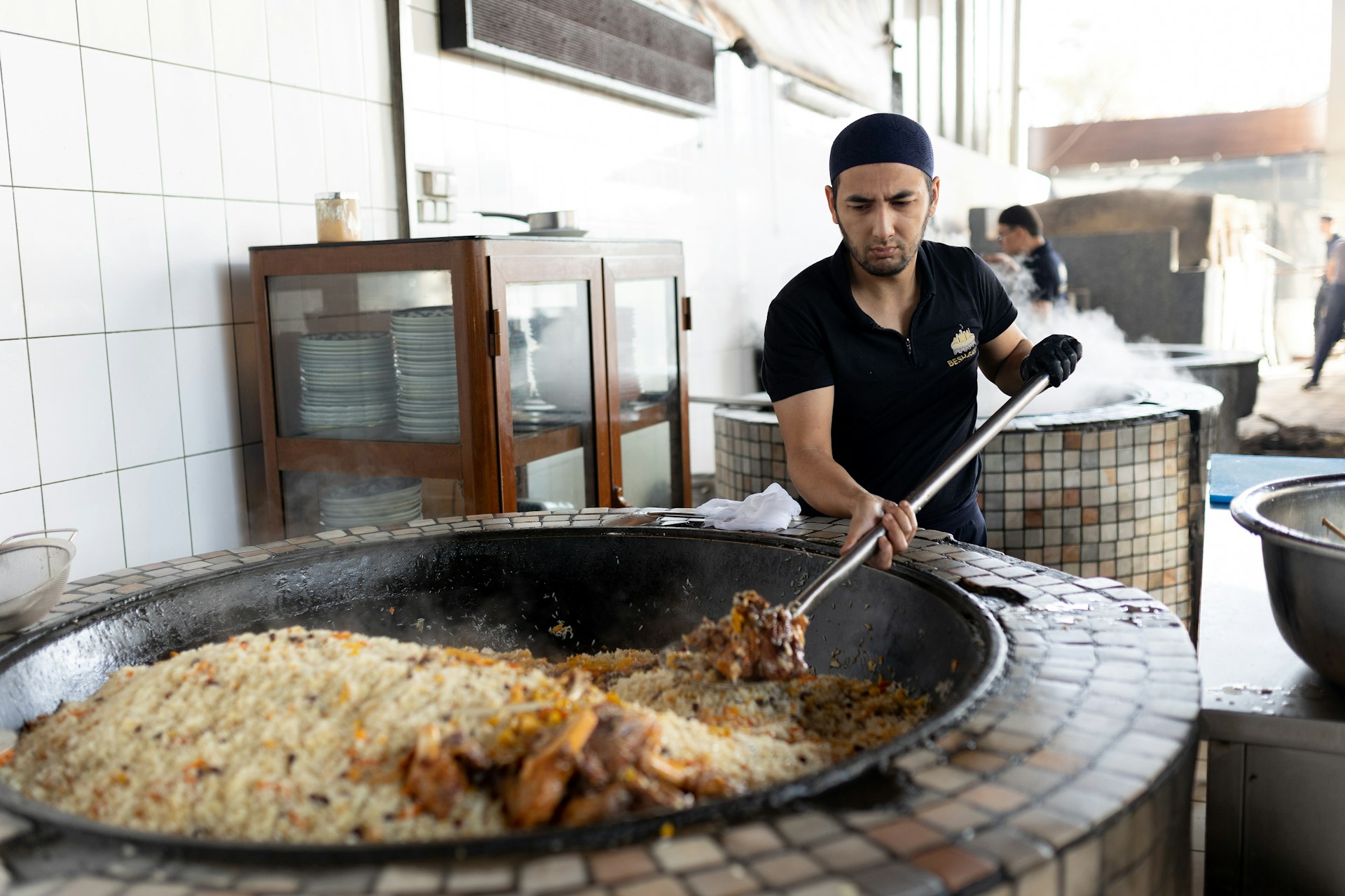 A chef prepares traditional Uzbek rice in a large cauldron