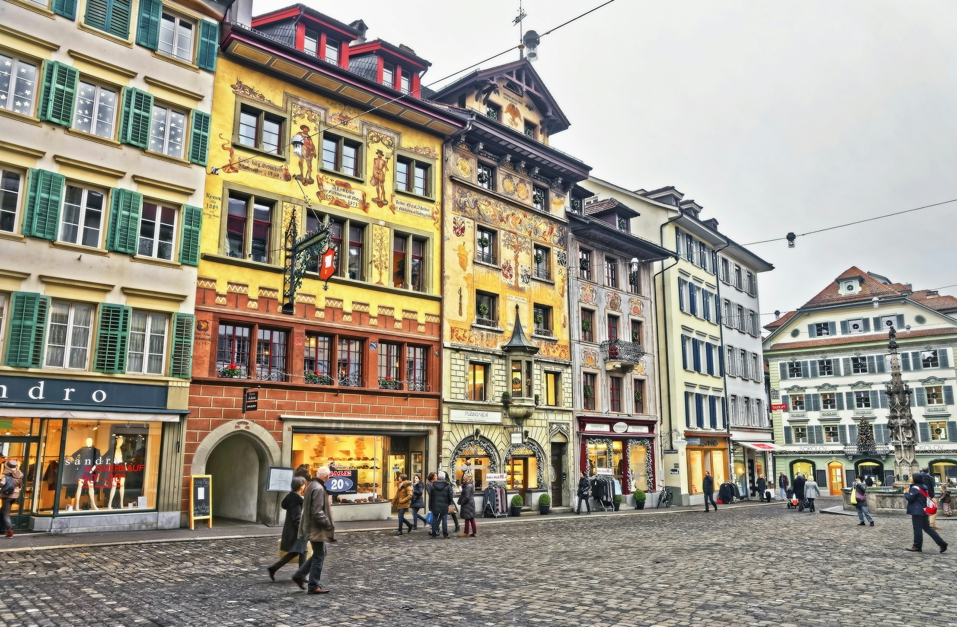 Medieval buildings covered in murals line a city square.