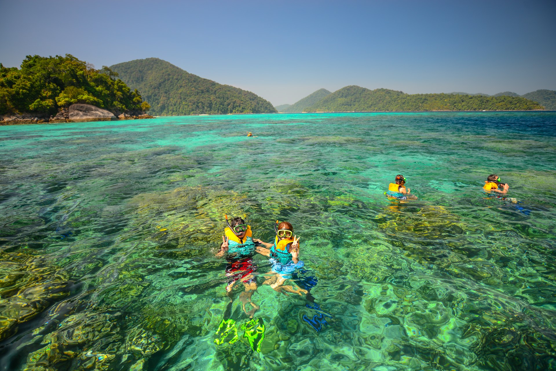 People snorkel in front of a beautiful coralscape at Surin National Park in Thailand. 