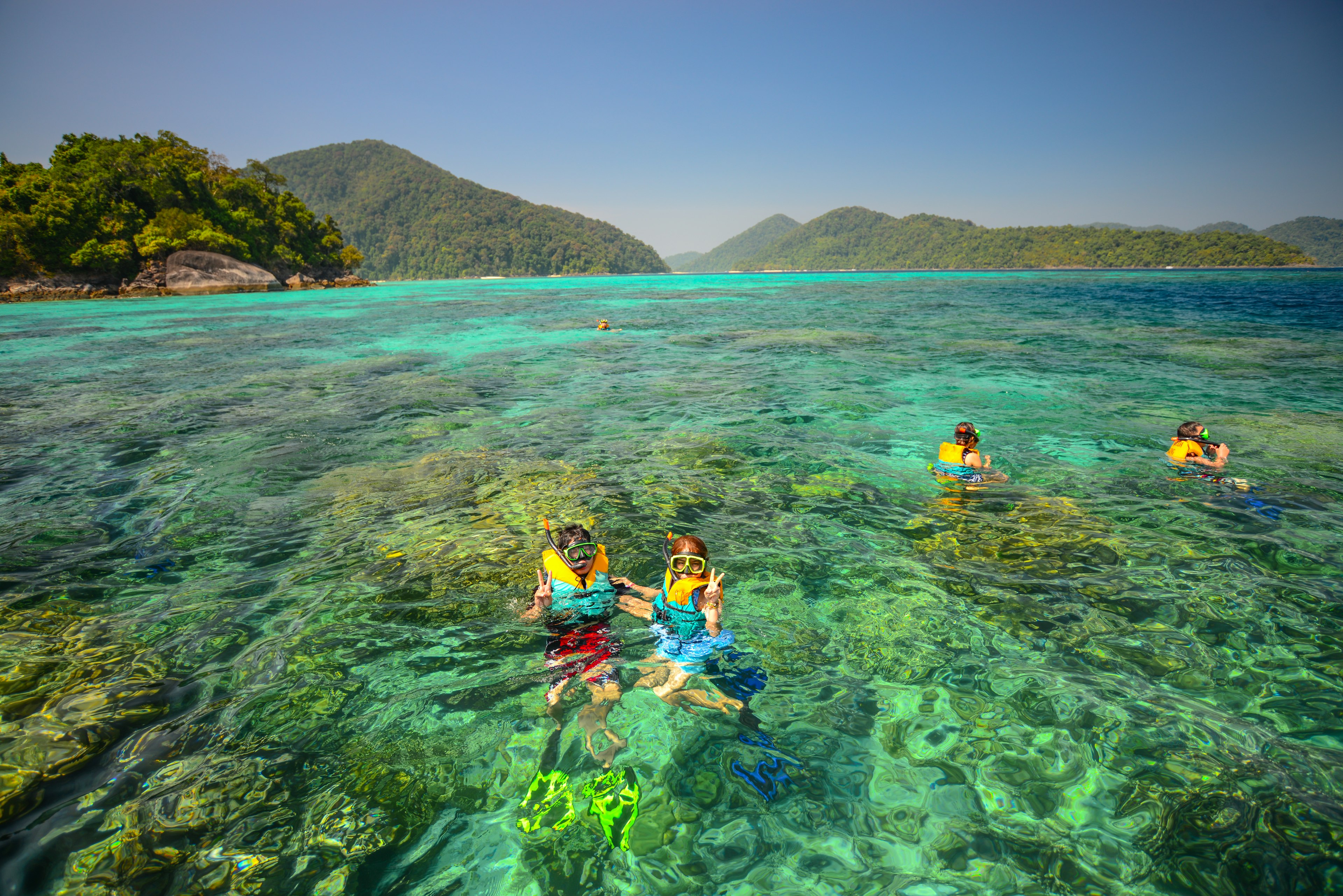 People snorkel in front of a beautiful coralscape at Surin National Park in Thailand.