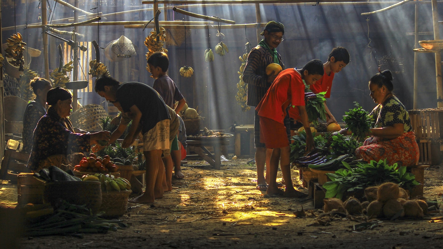 Jakarta residents shopping in a traditional market lit by shafts of light