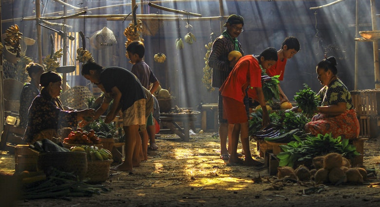 Jakarta residents shopping in a traditional market lit by shafts of light