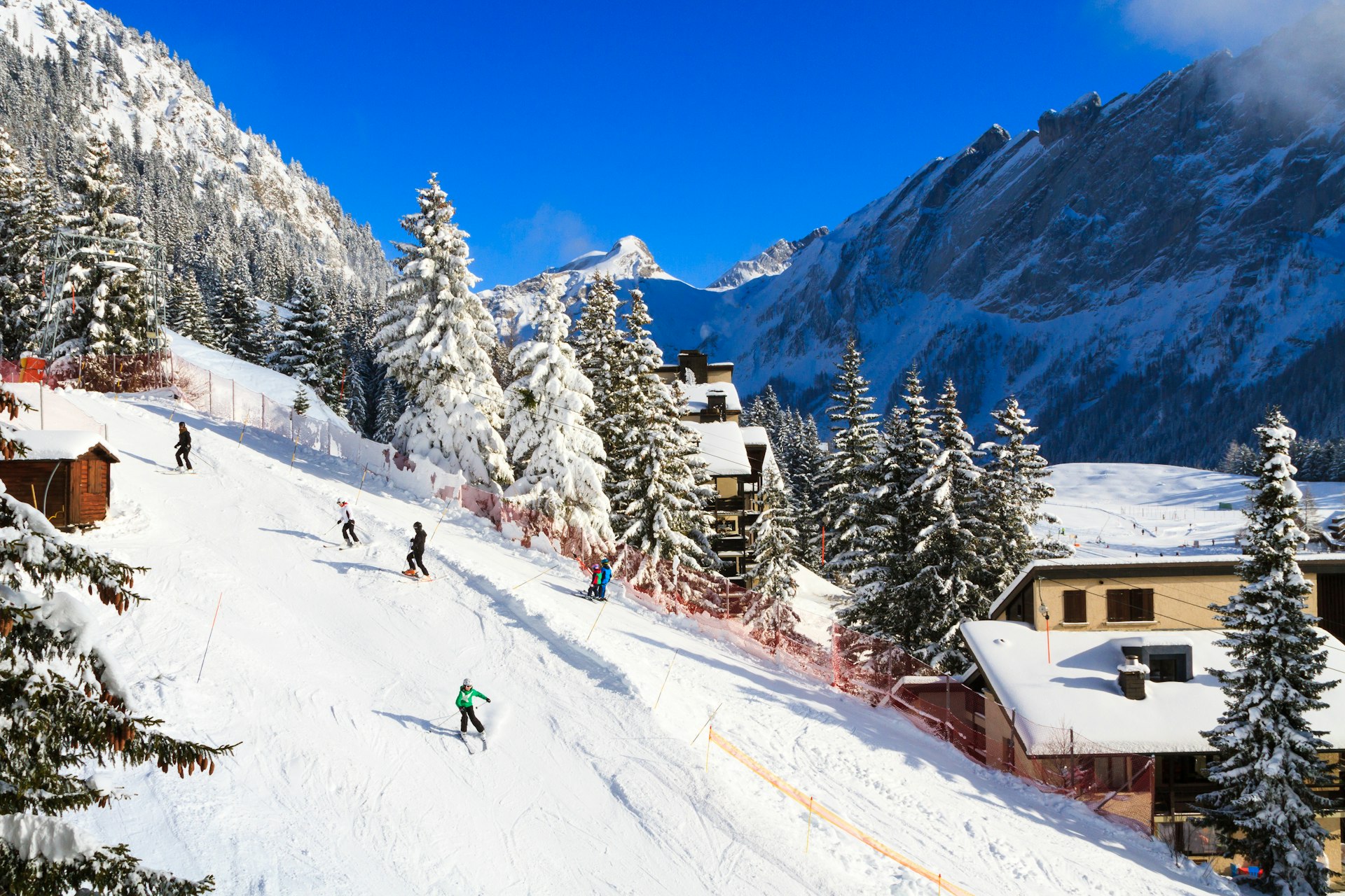 Skiiers make their way down a steep slope in Villars-sur-Ollon