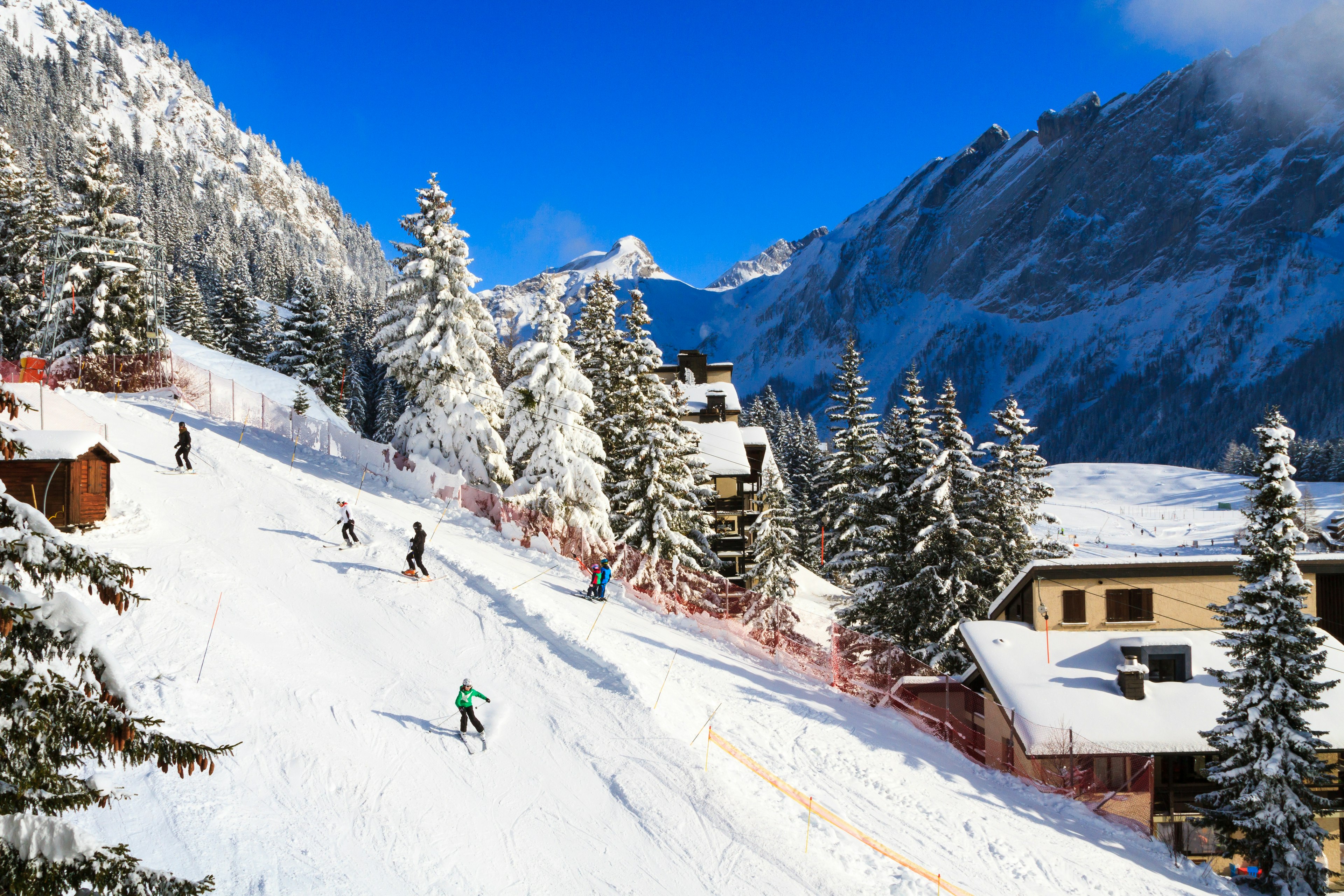 Skiiers make their way down a steep slope in Villars-sur-Ollon