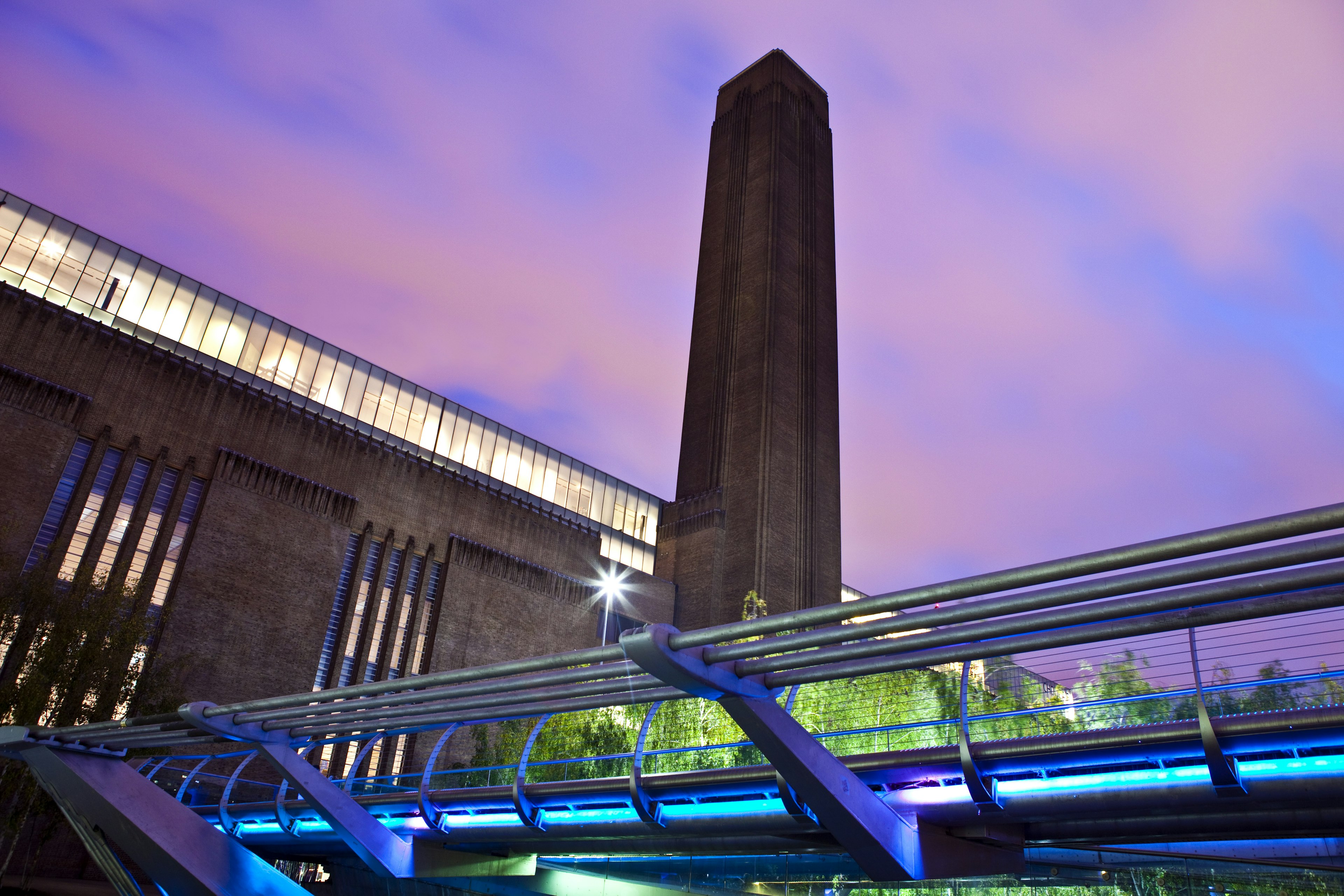 A large industrial building with a brick chimney at dusk