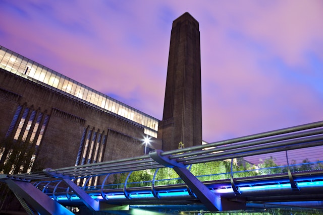A large industrial building with a brick chimney at dusk