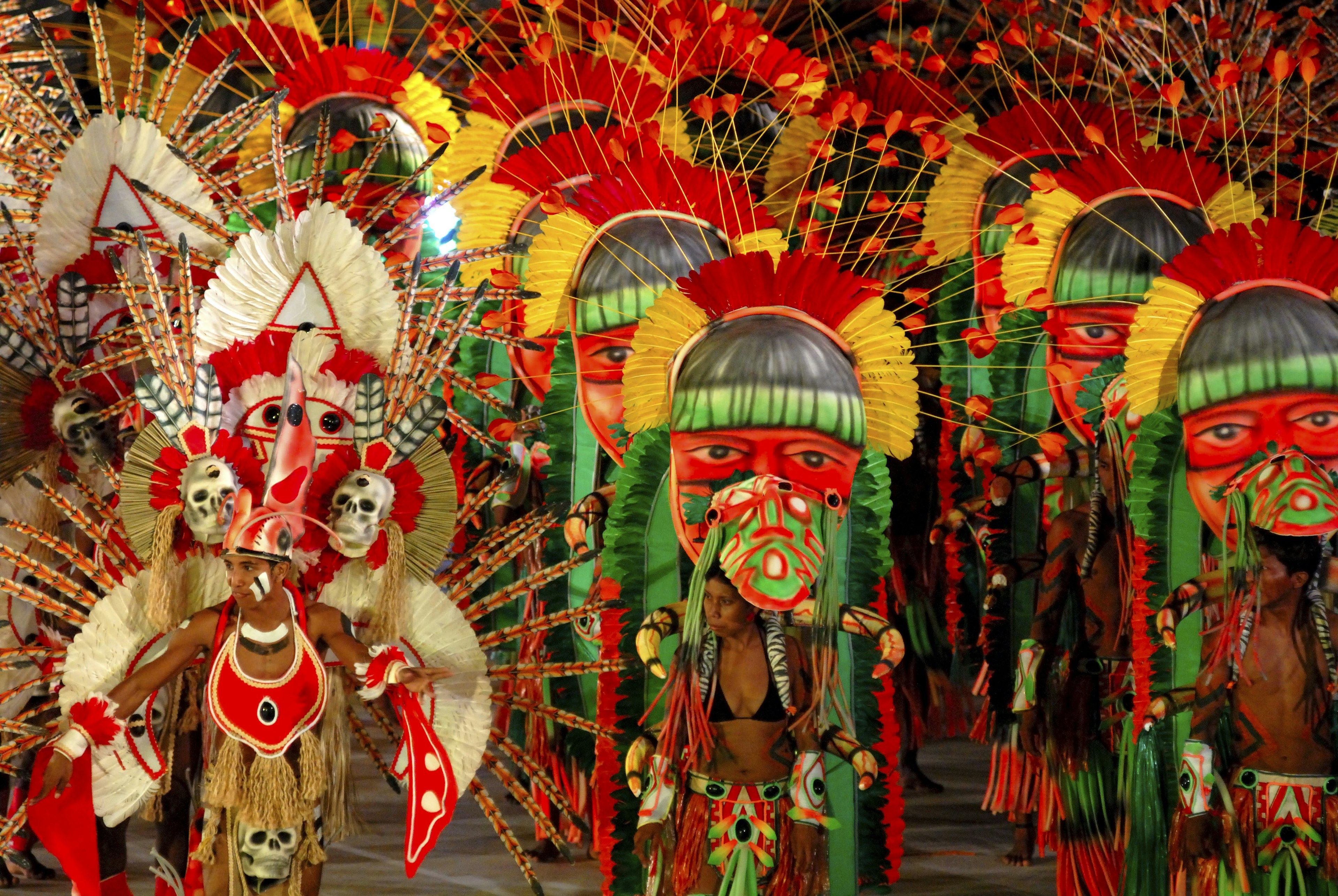 Costumed performers with large headresses in a parade at a festival