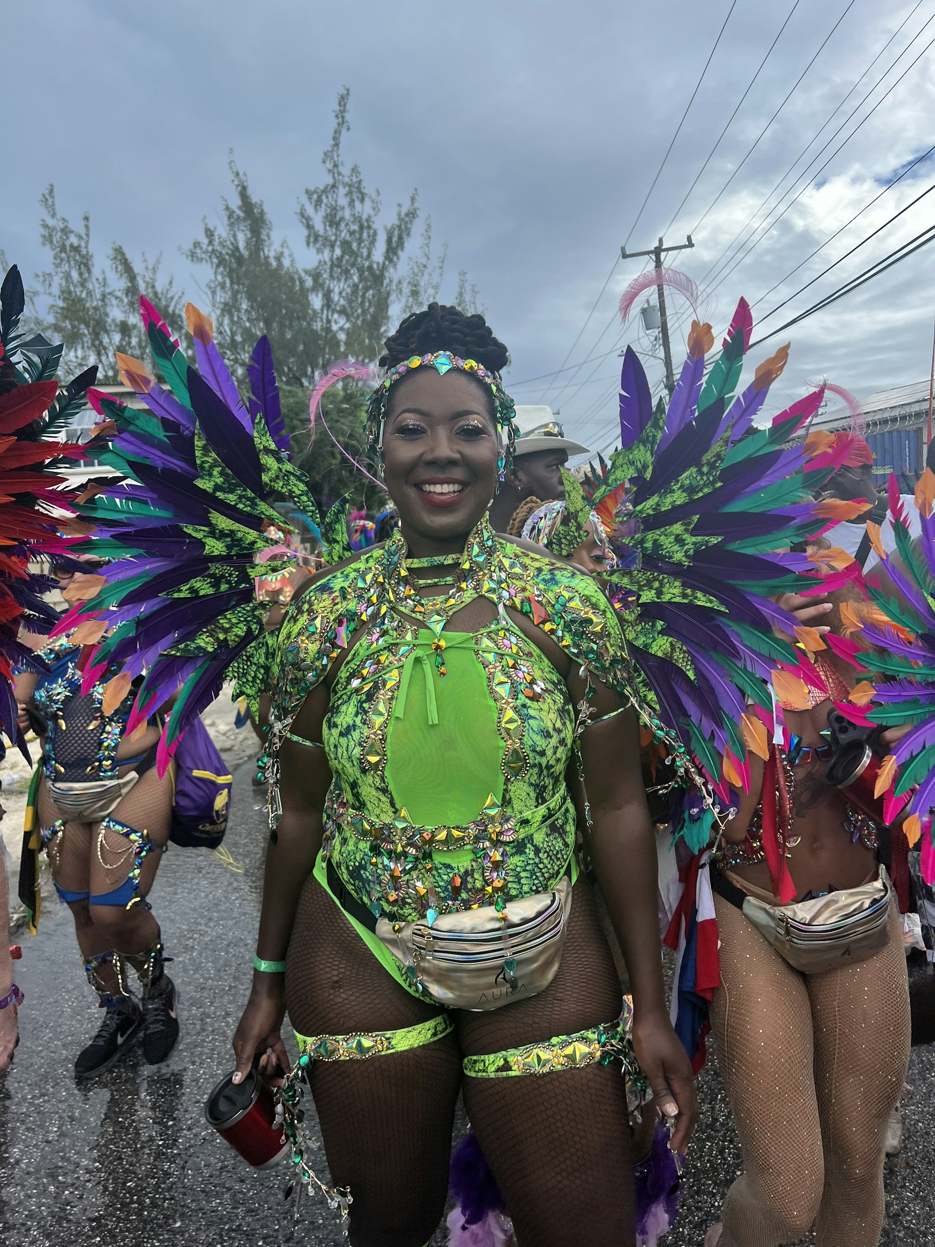 A woman stands smiling in a sparkly lime green Crop Over costume