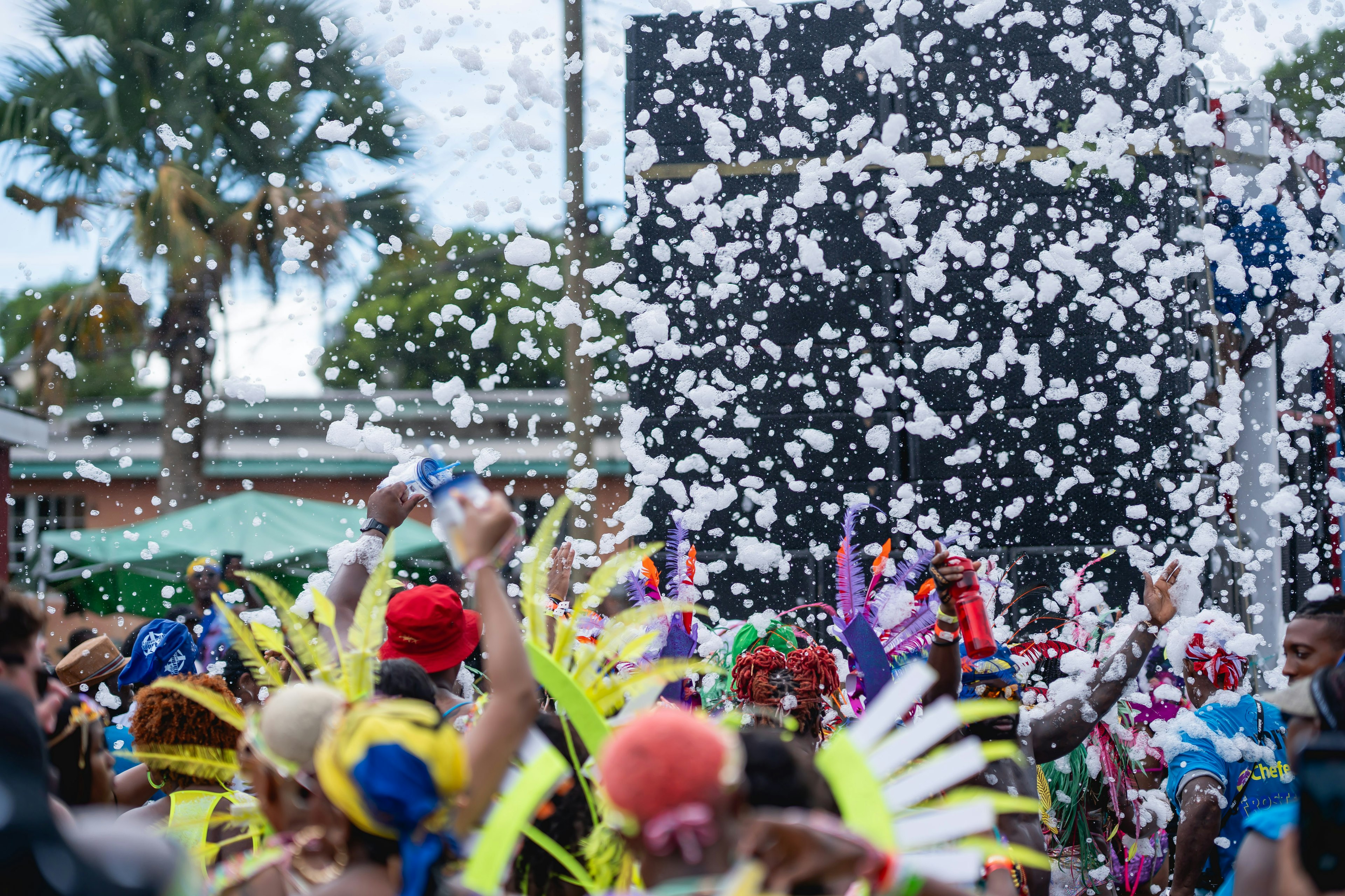 People wearing Crop Over outfits follow a large sound system, with foam flying in the air