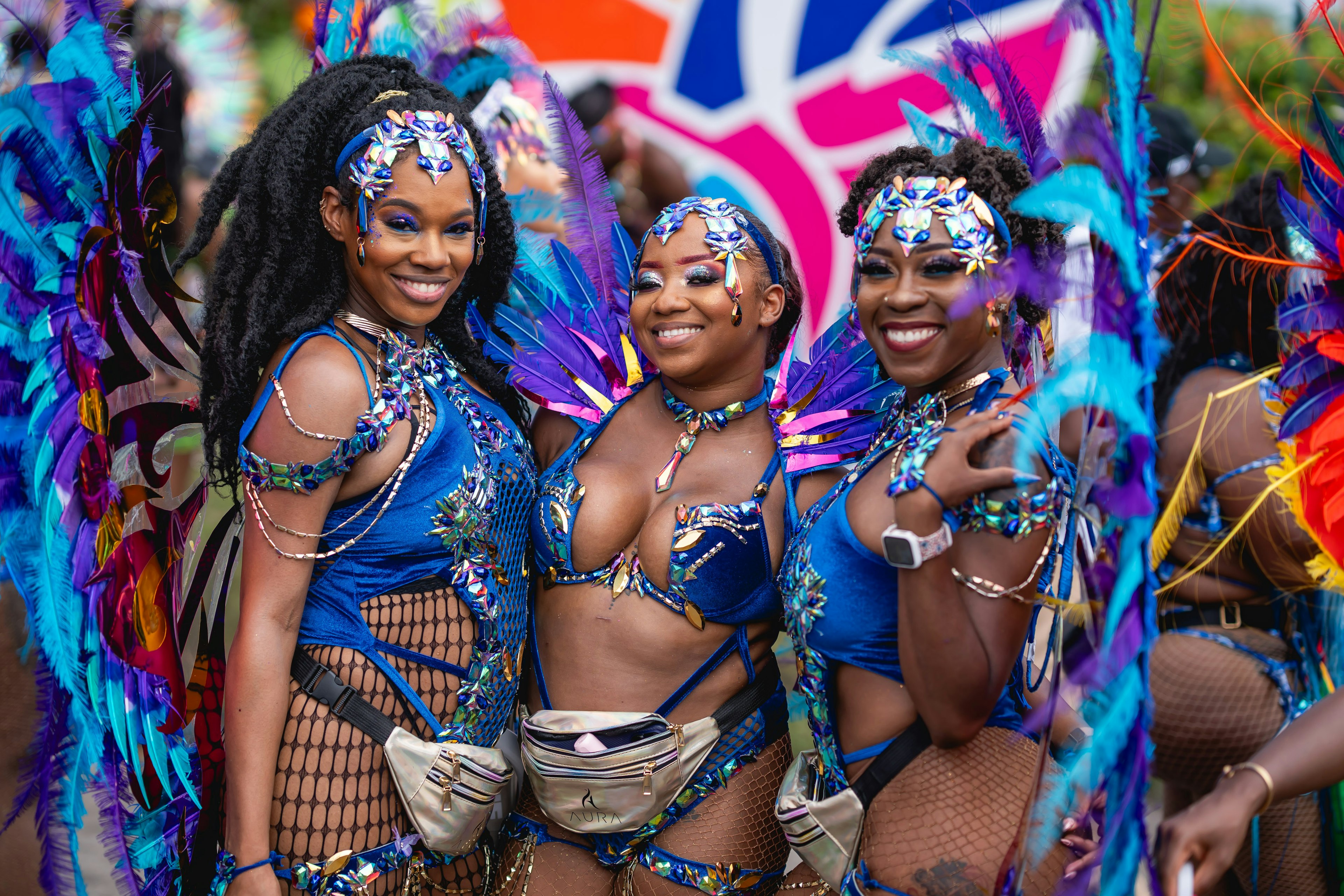 Three smiling women dressed in blue carnival-style costumes at Crop Over in Barbados