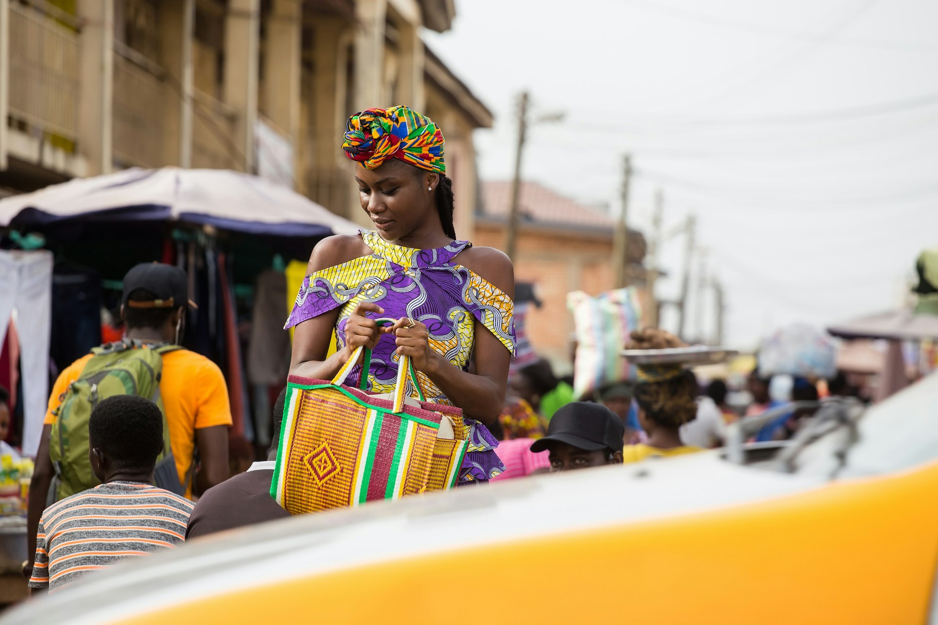 A young woman walking in the market in Accra, Ghana as a taxi passes
