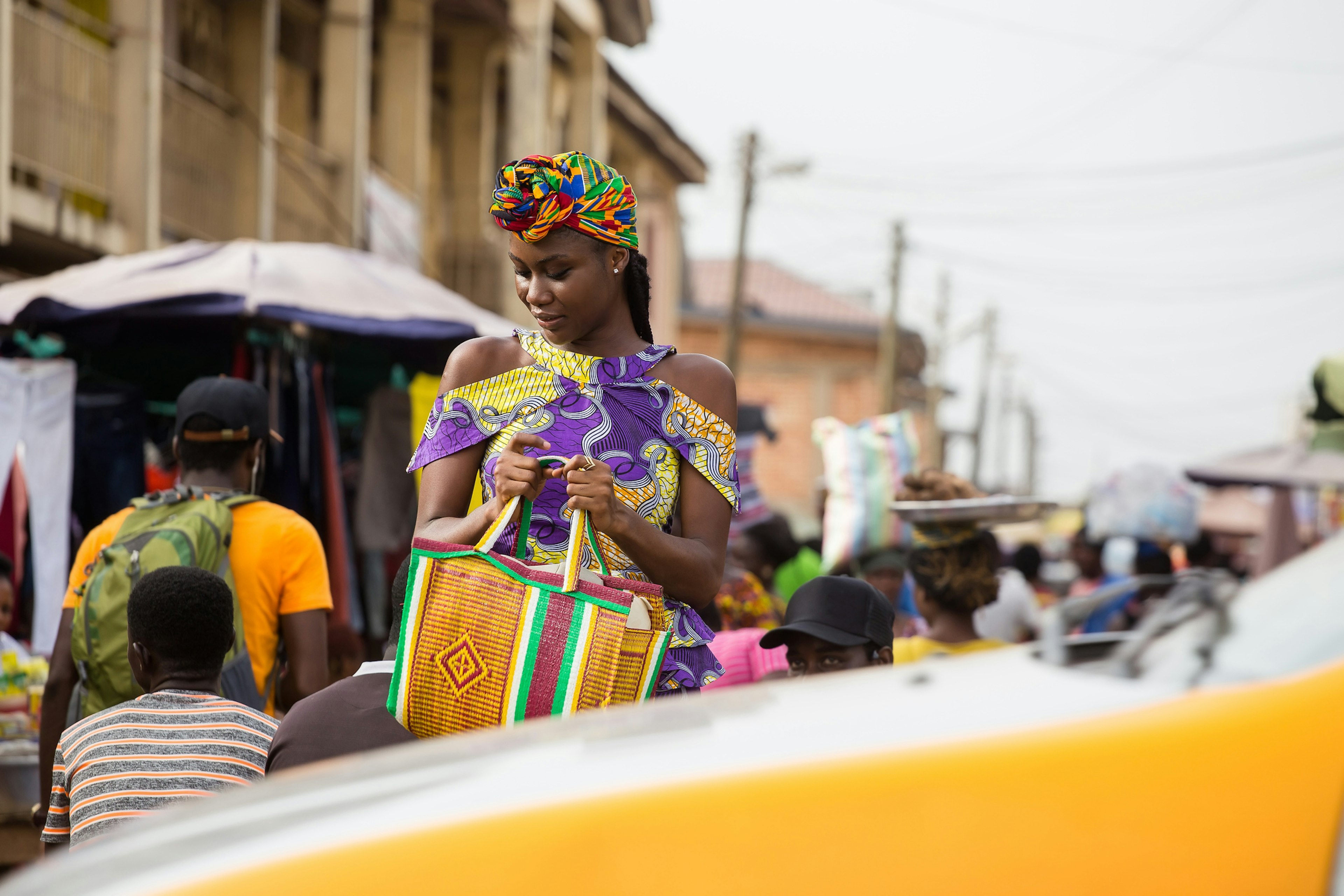 A young woman walking in the market in Accra, Ghana as a taxi passes