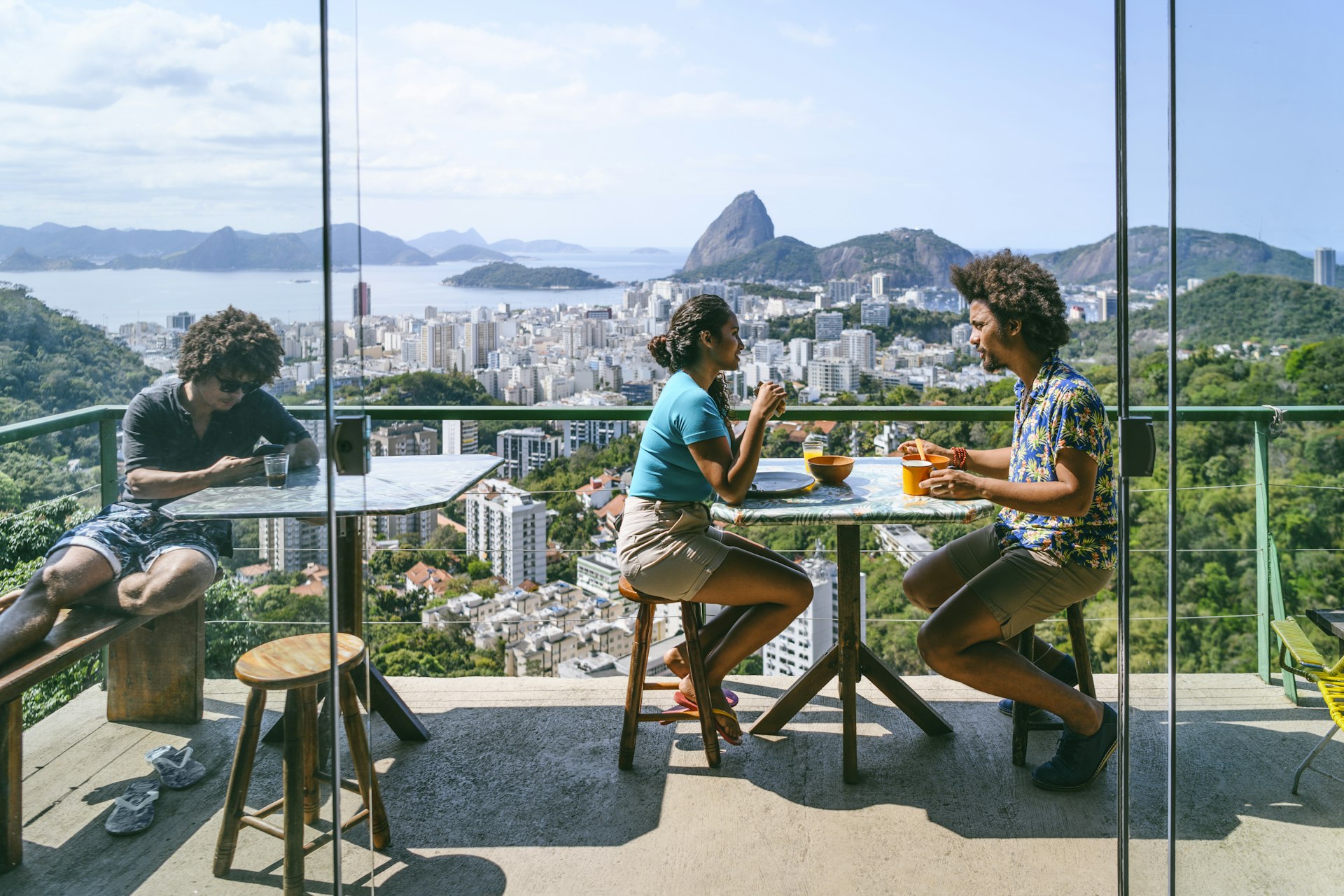 Two people talk on a balcony overlooking Rio de Janiero