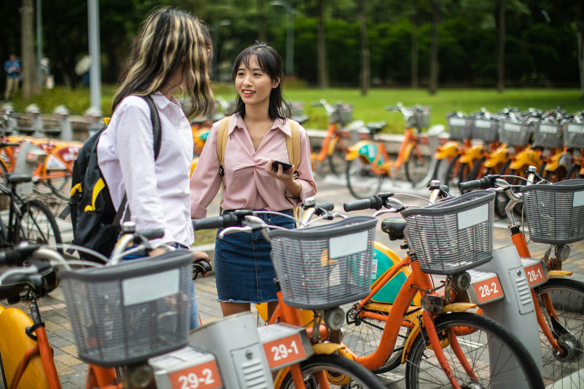 Two young women renting bikes together in a park in Taipei, Taiwan