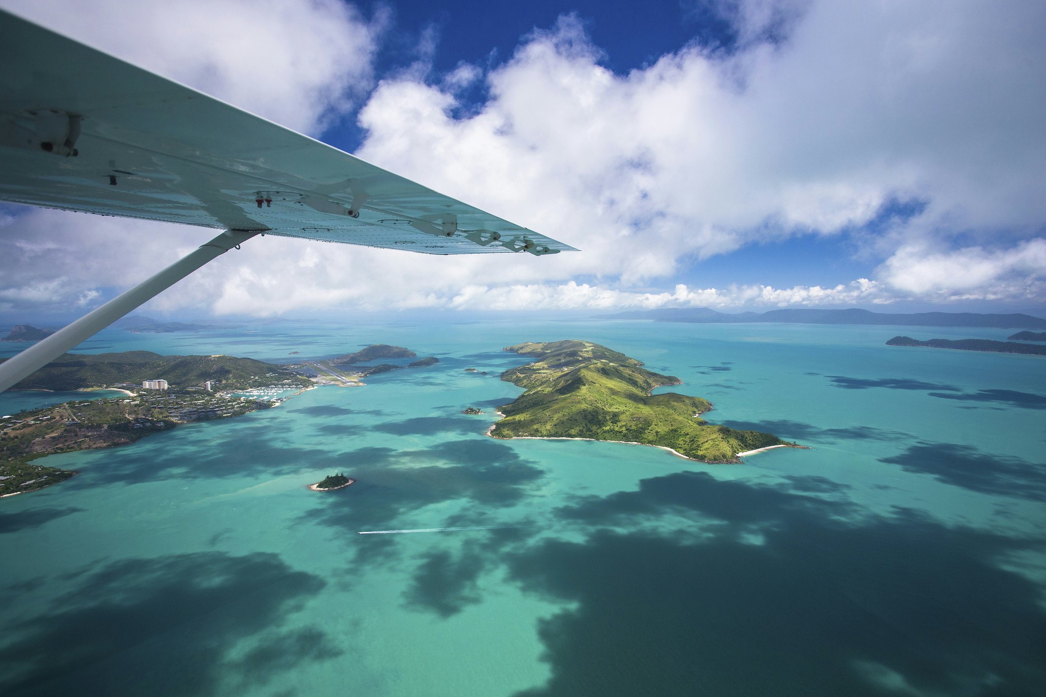 A small plane flies over island scenery.