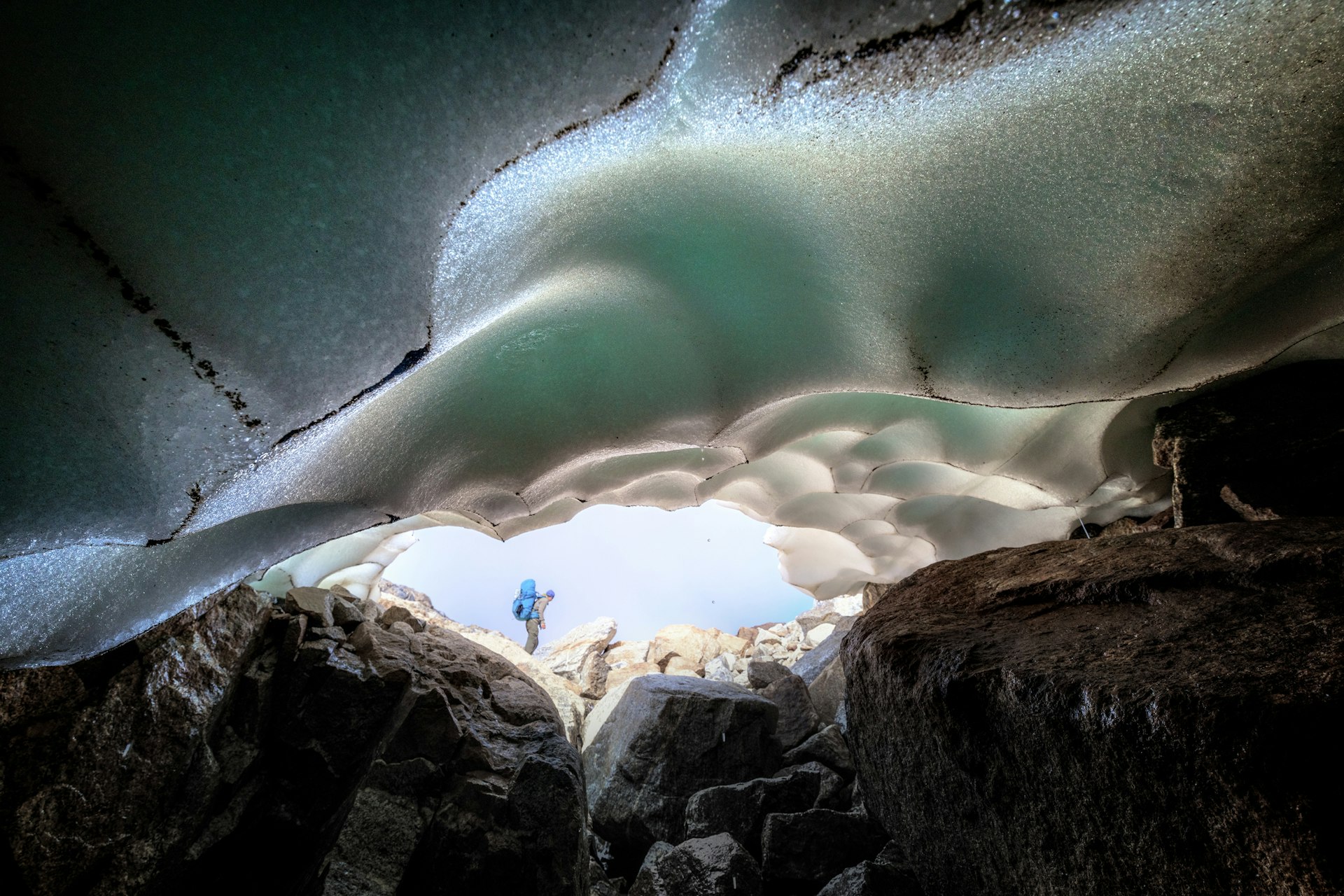 A man walks acros the pass over Imertivap near Tasiilaq in East Greenland and is seen through a cave with snow all around