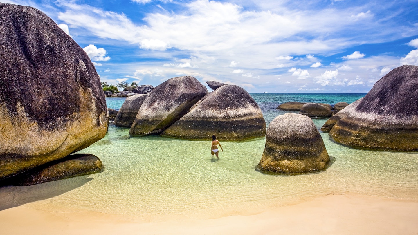 Indonesia, Bangka-Belitung, Belitung Island, woman wading in shallow water at beach with granite boulders
1205427427