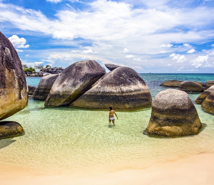 Indonesia, Bangka-Belitung, Belitung Island, woman wading in shallow water at beach with granite boulders
1205427427