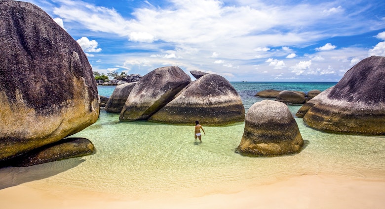 Indonesia, Bangka-Belitung, Belitung Island, woman wading in shallow water at beach with granite boulders
1205427427