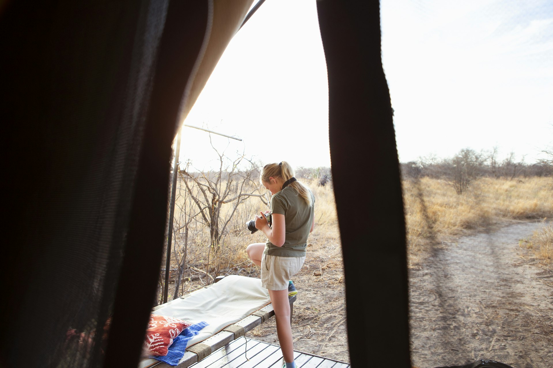 A teenage girl looks through her camera shots at a Botswana camp