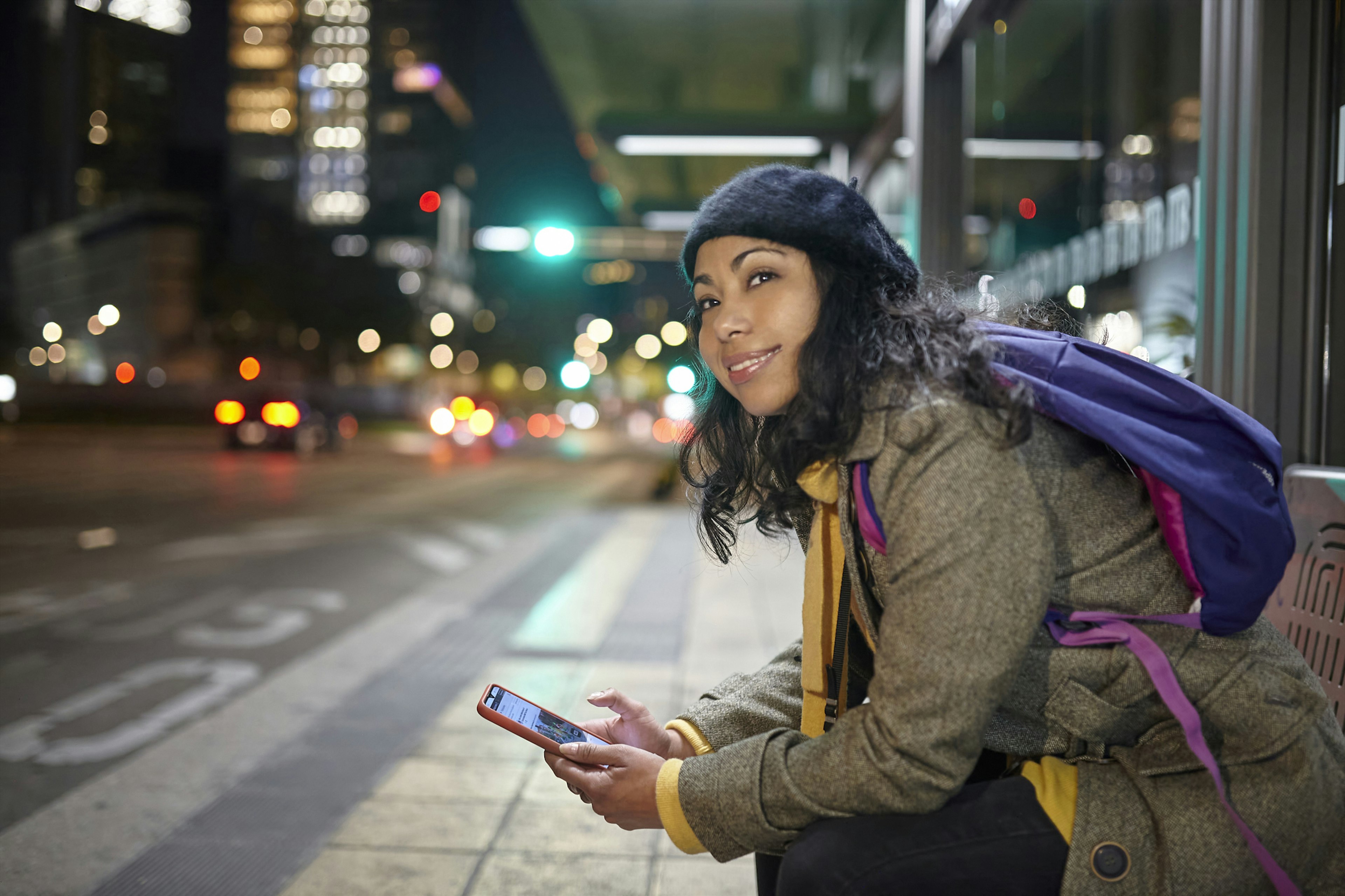 A woman sits at a bus stop at night in Mexico City waiting for a bus