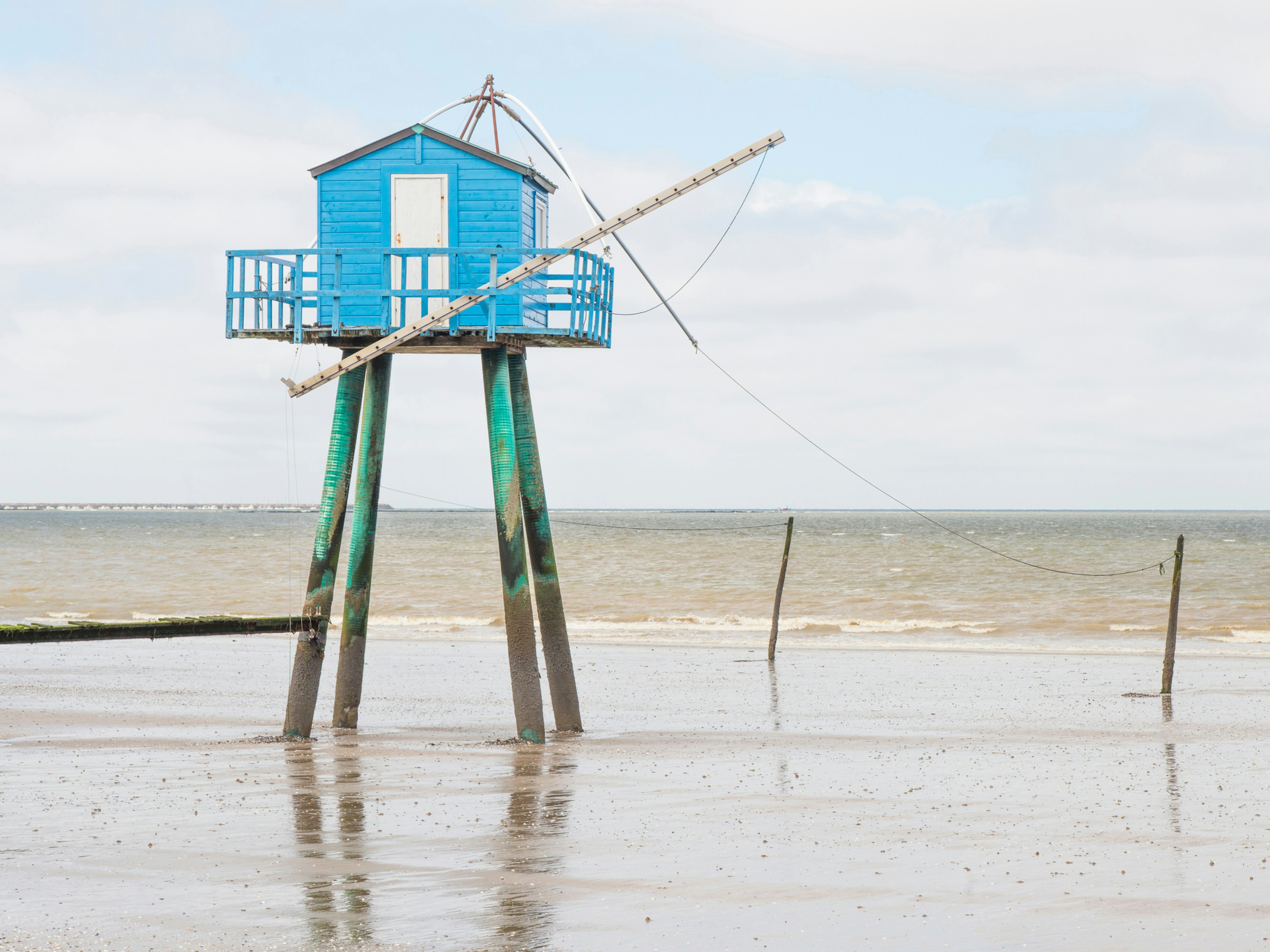 a blue wooden fishing hut stands out in the sea at Pornic