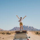 Young woman with long hair feeling freedom staying on the roof tent of the 4X4 camper truck, contemplating the road trip along the dramatic mountain landscape in Spitzkoppe
1364754727
