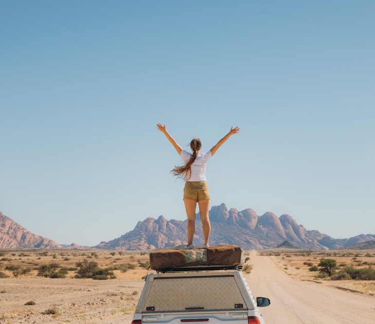 Young woman with long hair feeling freedom staying on the roof tent of the 4X4 camper truck, contemplating the road trip along the dramatic mountain landscape in Spitzkoppe
1364754727