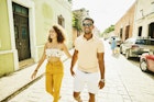 A smiling couple walking down a street in Mexico while holding hands