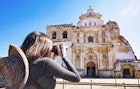 A young woman taking a picture of San Francisco Church, Antigua - Guatemala