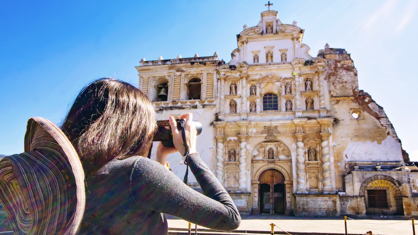 A young woman taking a picture of San Francisco Church, Antigua - Guatemala