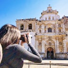 A young woman taking a picture of San Francisco Church, Antigua - Guatemala