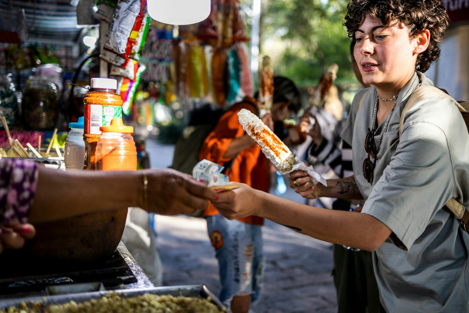 A woman pays for a sweetcorn on a stick at a street food stall in Mexico