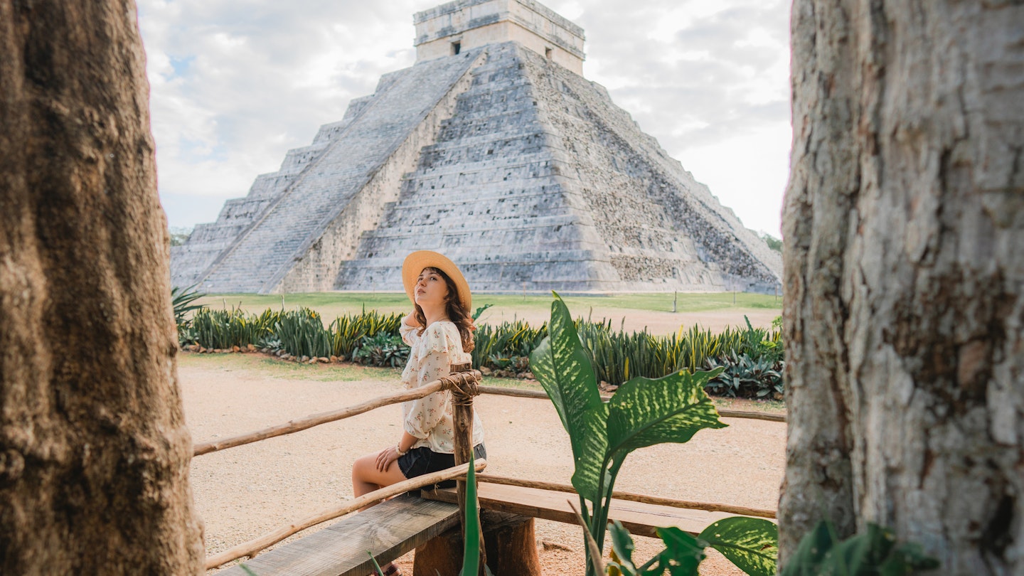 A woman sitting near the main pyramid at Chichen Itza in Mexico