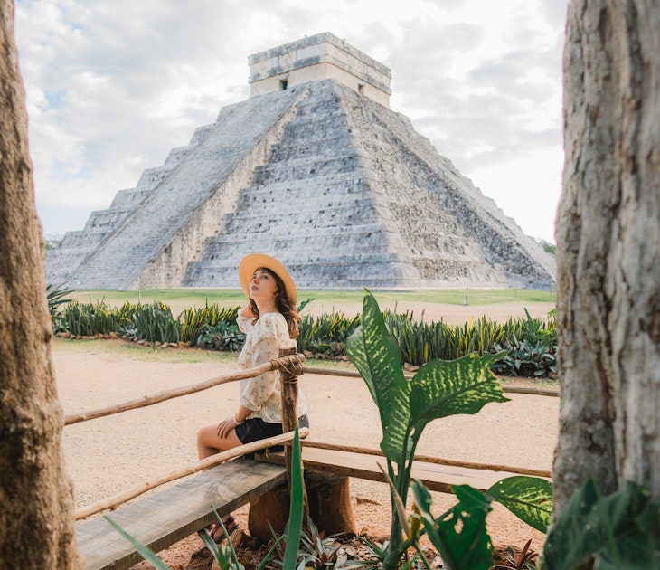 A woman sitting near the main pyramid at Chichen Itza in Mexico