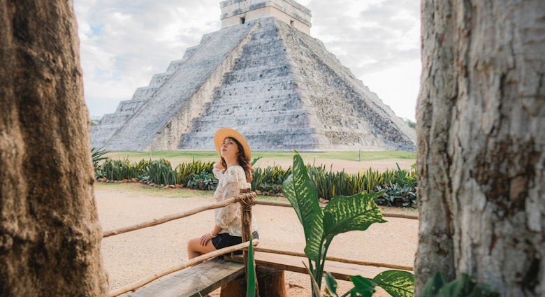 A woman sitting near the main pyramid at Chichen Itza in Mexico