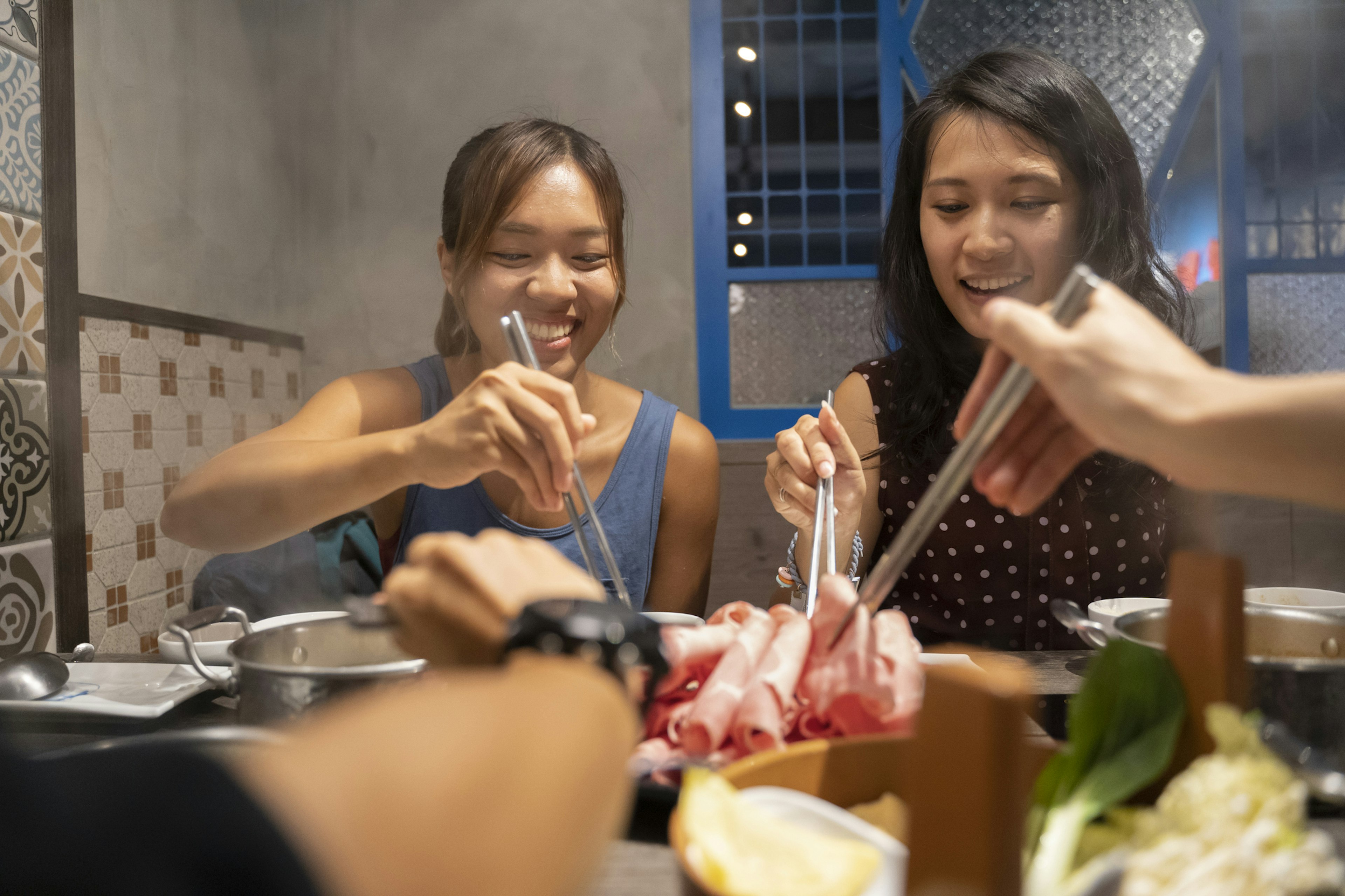 A group of friends share dinner together at a table laden with many dishes