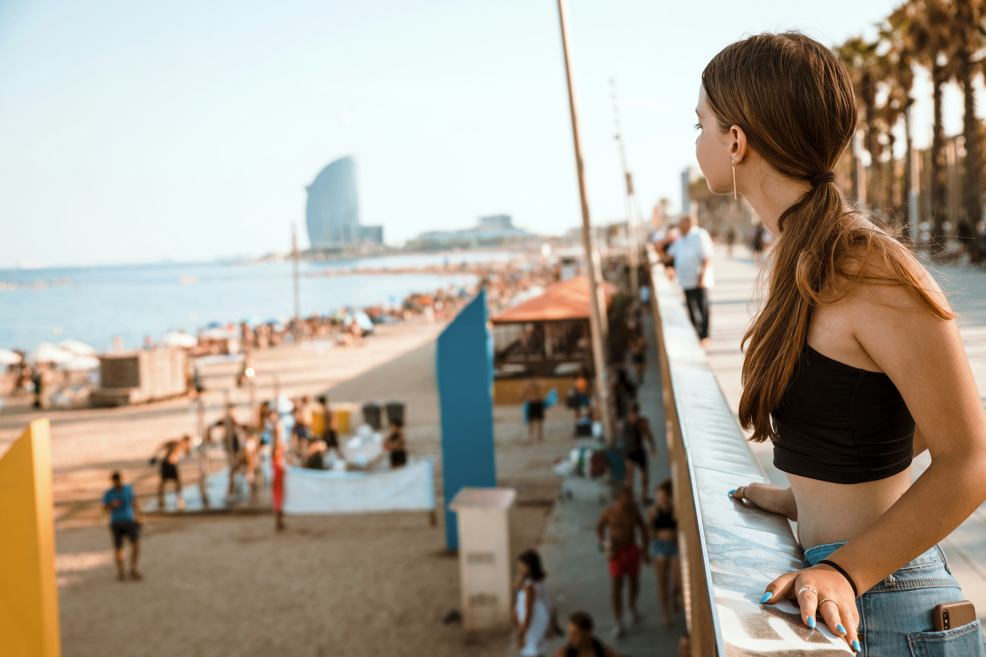 A teen girl looks out over the beach in Barcelona