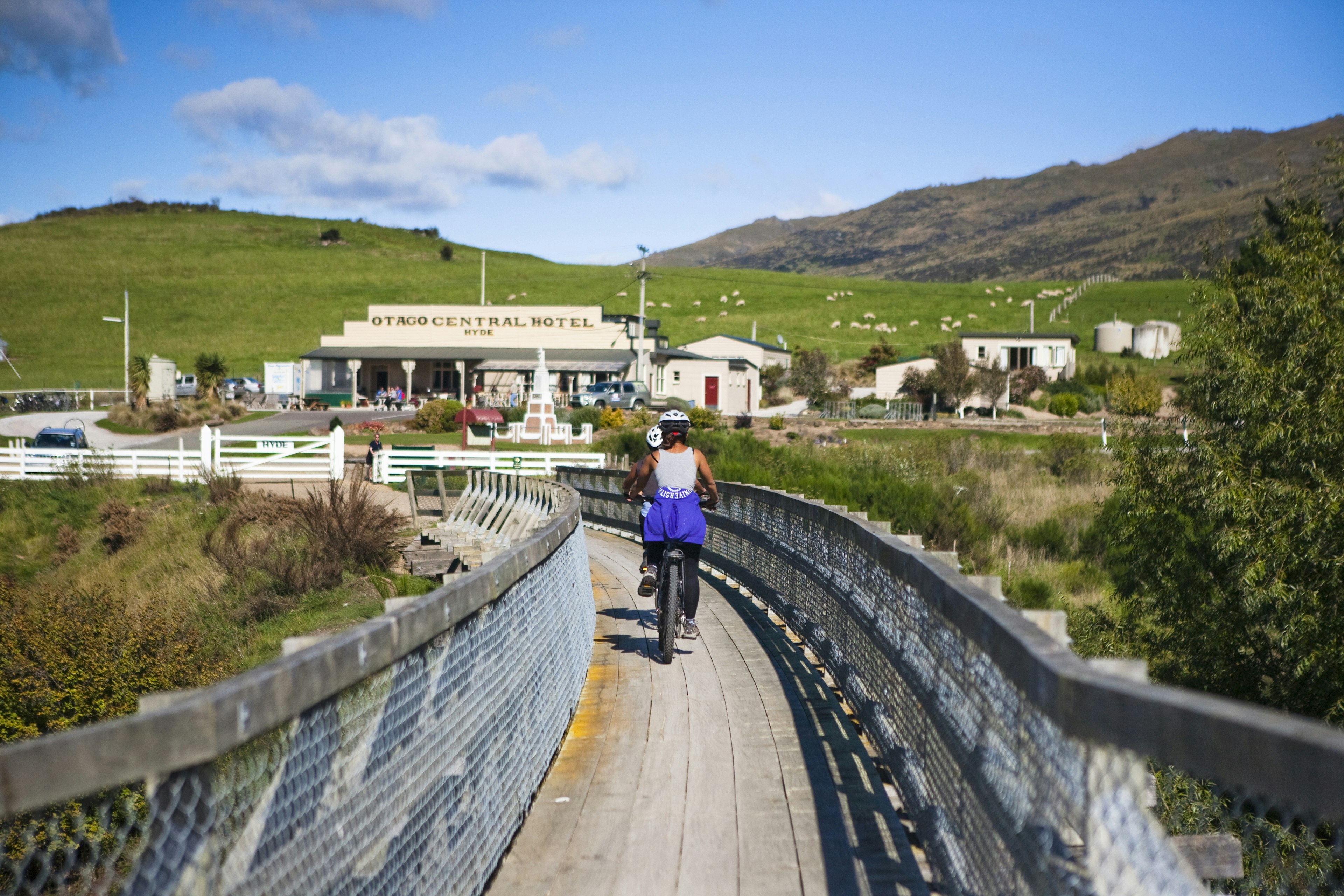 People cycling along a wooden bridge in Central Otago in New Zealand