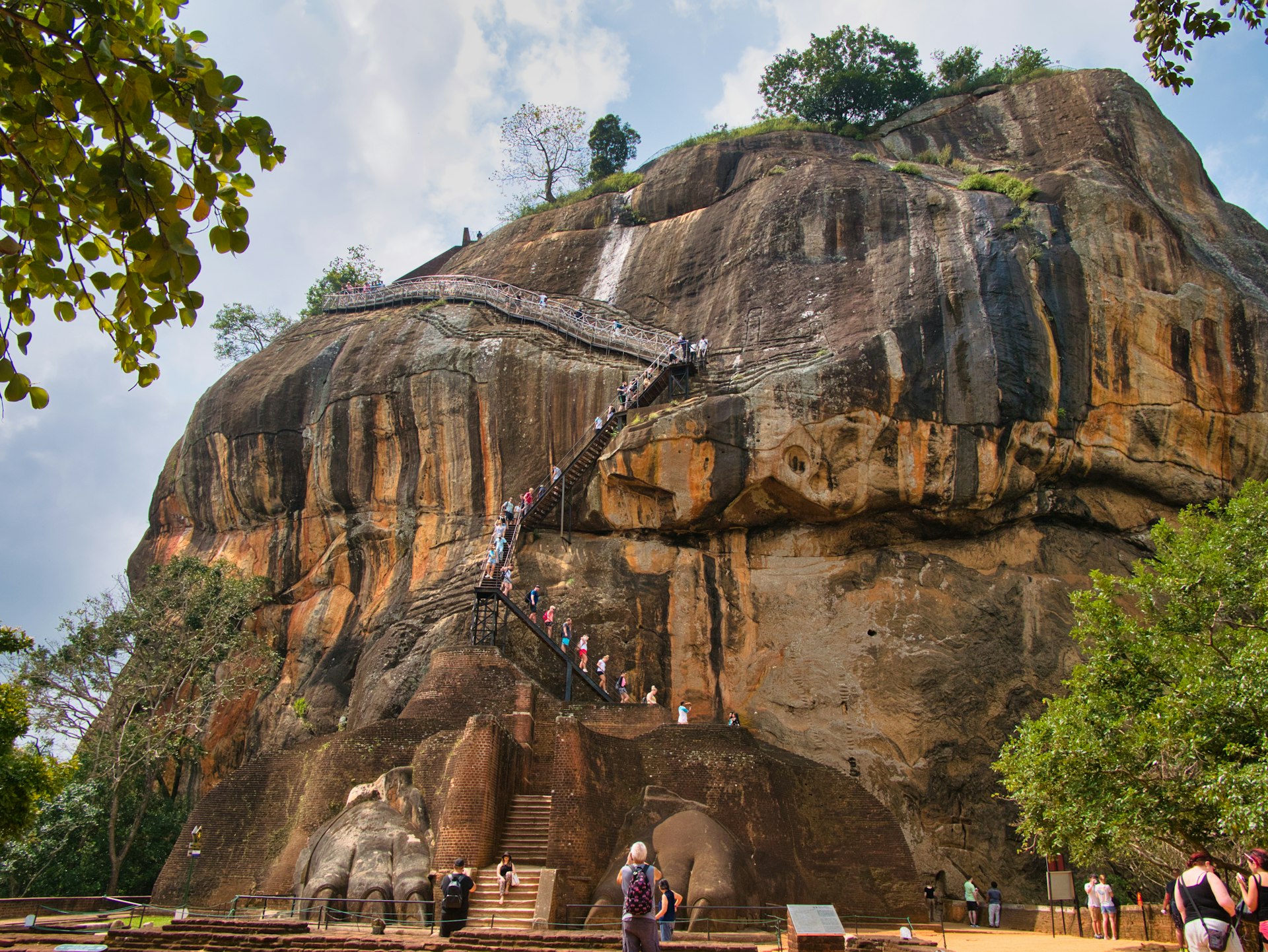 Above the Lion Gate, many tourists ascend and descend the steep stairs to the top of the ancient rock fortress of Sigiriya or Lion Rock in central Sri Lanka
