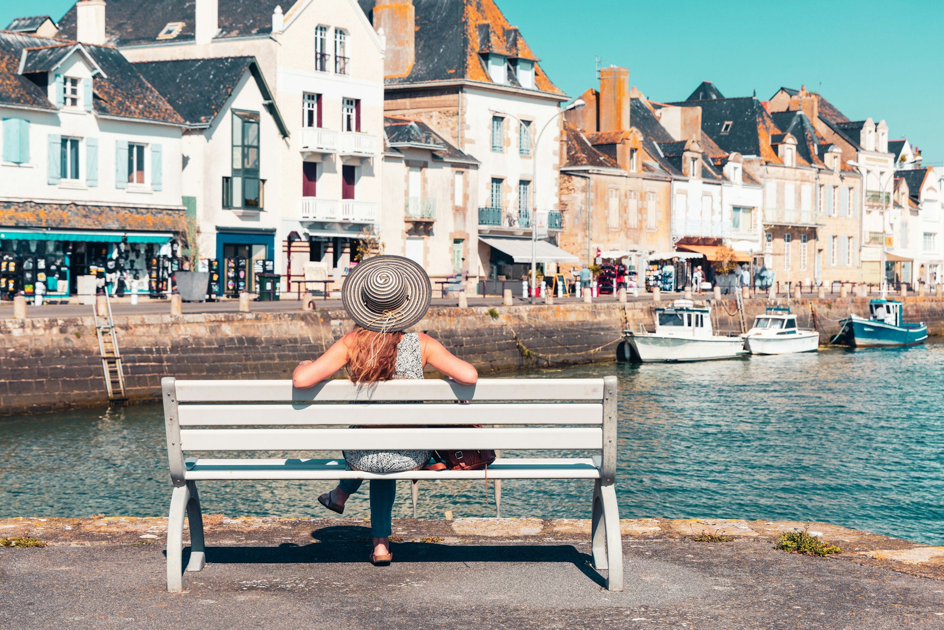 Woman tourist sitting on bench enjoying view of Le Croisic village and port- Loire-Atlantic in France