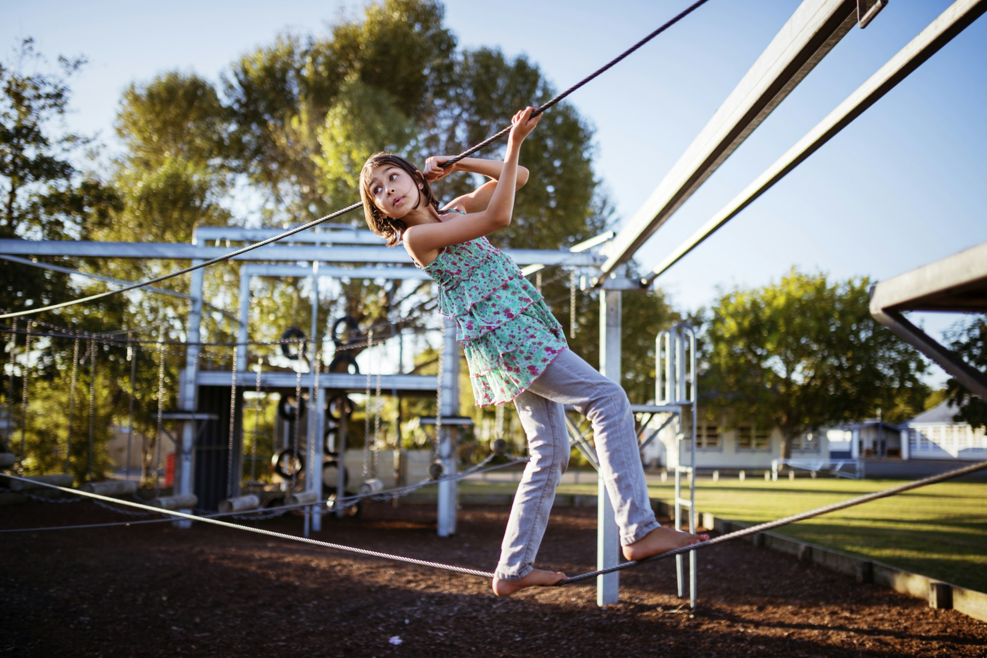Young girl walks on a tightrope in a playground, New Zealand